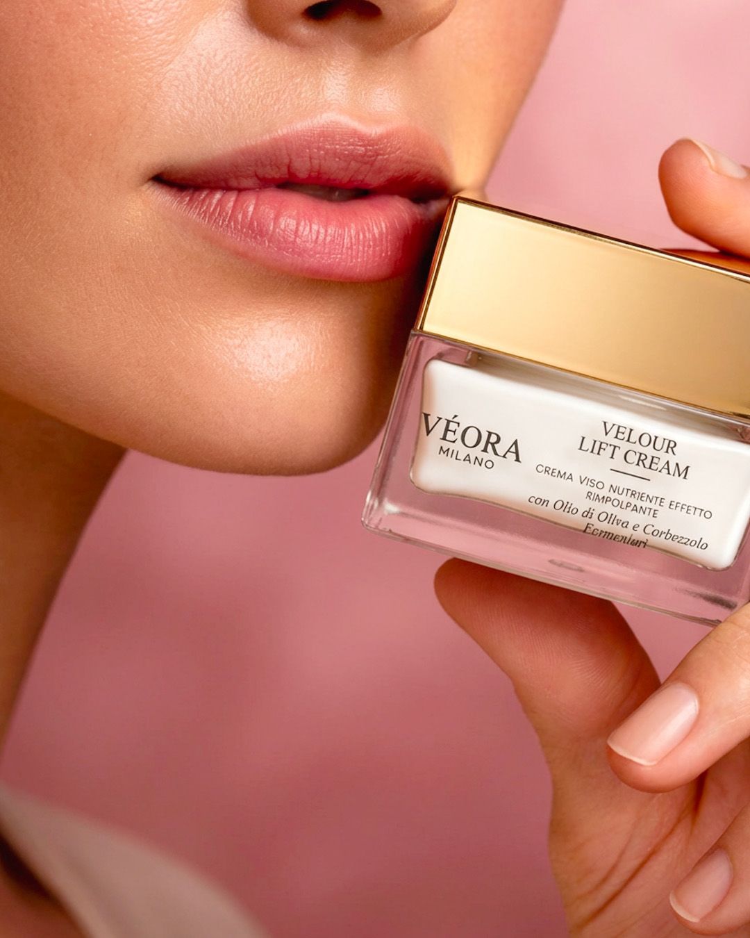 Persona che tiene in mano un vasetto di crema Véora Milano su sfondo rosa