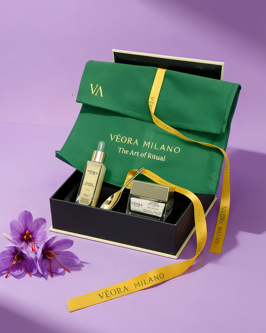 Set di prodotti per la cura della pelle Véora Milano Collezione Saffron con pochette in raso verde su sfondo viola.